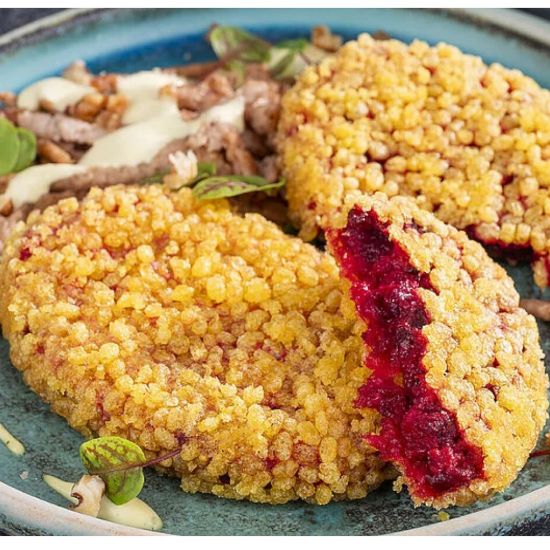 Bild von Rote Bete Puffer 80g, vegan mit der Beschreibung Puffer aus Rote Beete-Stücken, Kichererbsen, Gurken & Zwiebelwürfeln in einer knusprigen Maispanade.